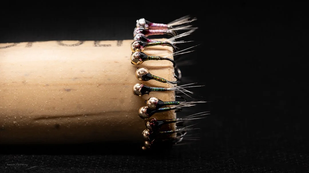 Close-up of fishing hooks attached to a wooden dowel against a black background.