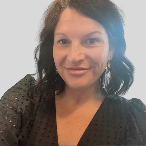 A woman with shoulder-length dark hair wearing a black top with textured dots, smiling at the camera with a plain light background.