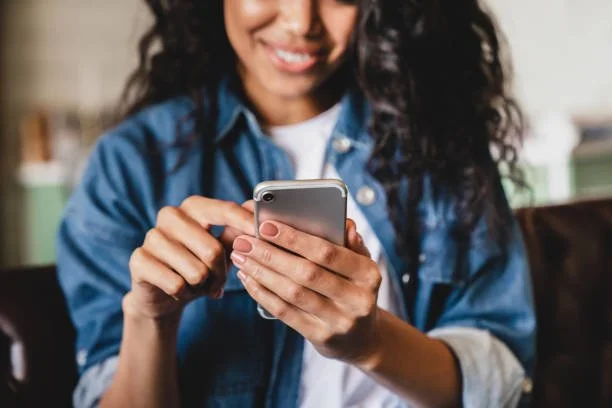 Woman smiling while using smartphone indoors
