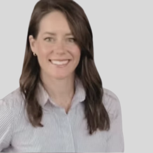 A woman with shoulder-length brown hair, smiling, wearing a light-colored button-up shirt, against a plain background.