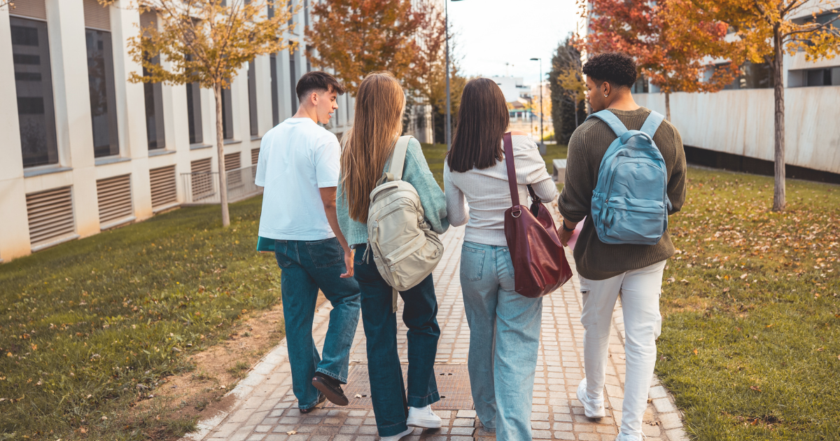 Four young adults walking together along an autumn campus path, representing the transition to adulthood with ADHD