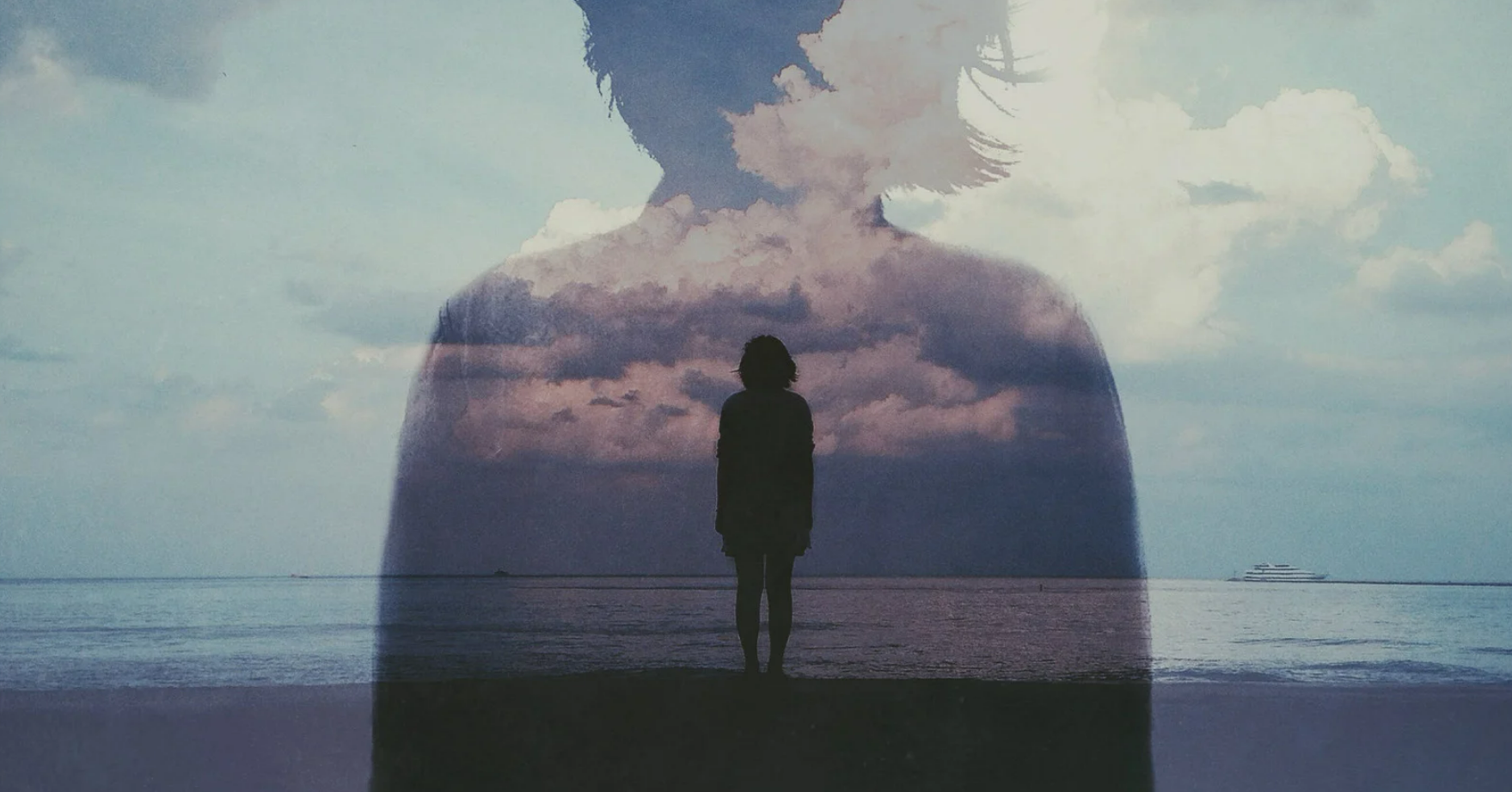 Silhouette of a person standing at the beach looking out to sea.