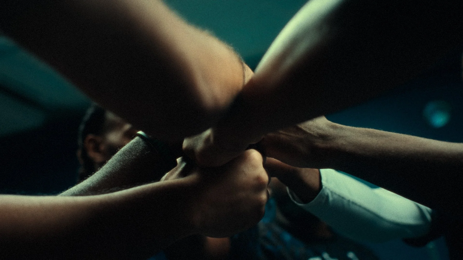 Close-up of multiple hands gripping each other's wrists in a group gesture