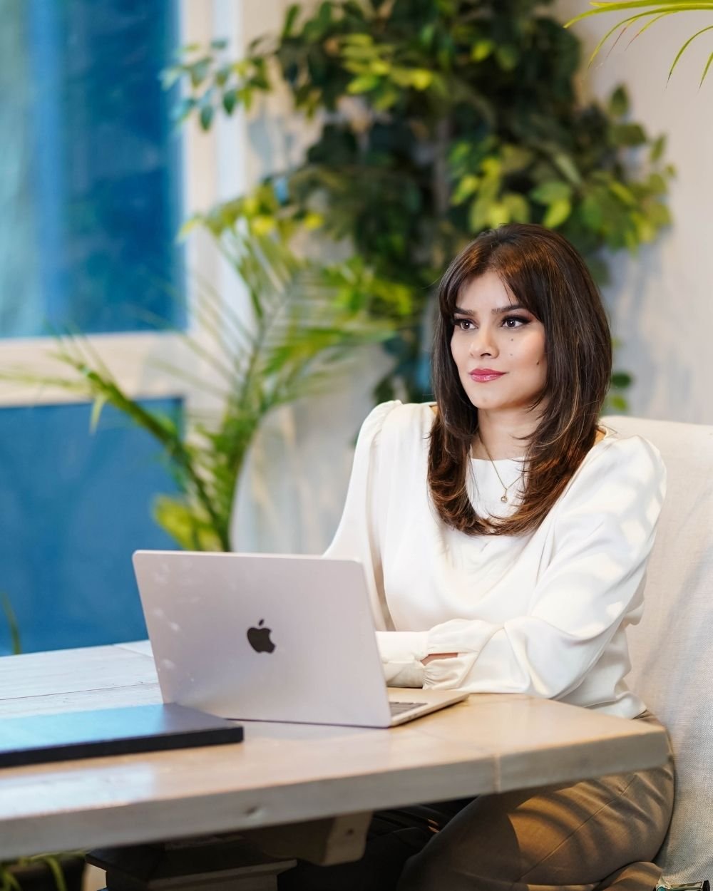 Ayesha sitting at a desk with a laptop at Art of Becoming Counselling