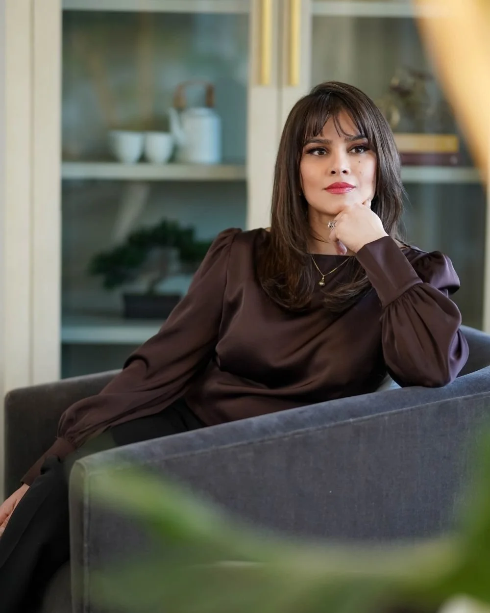 Ayesha sitting on a gray couch at Art of Becoming Counselling