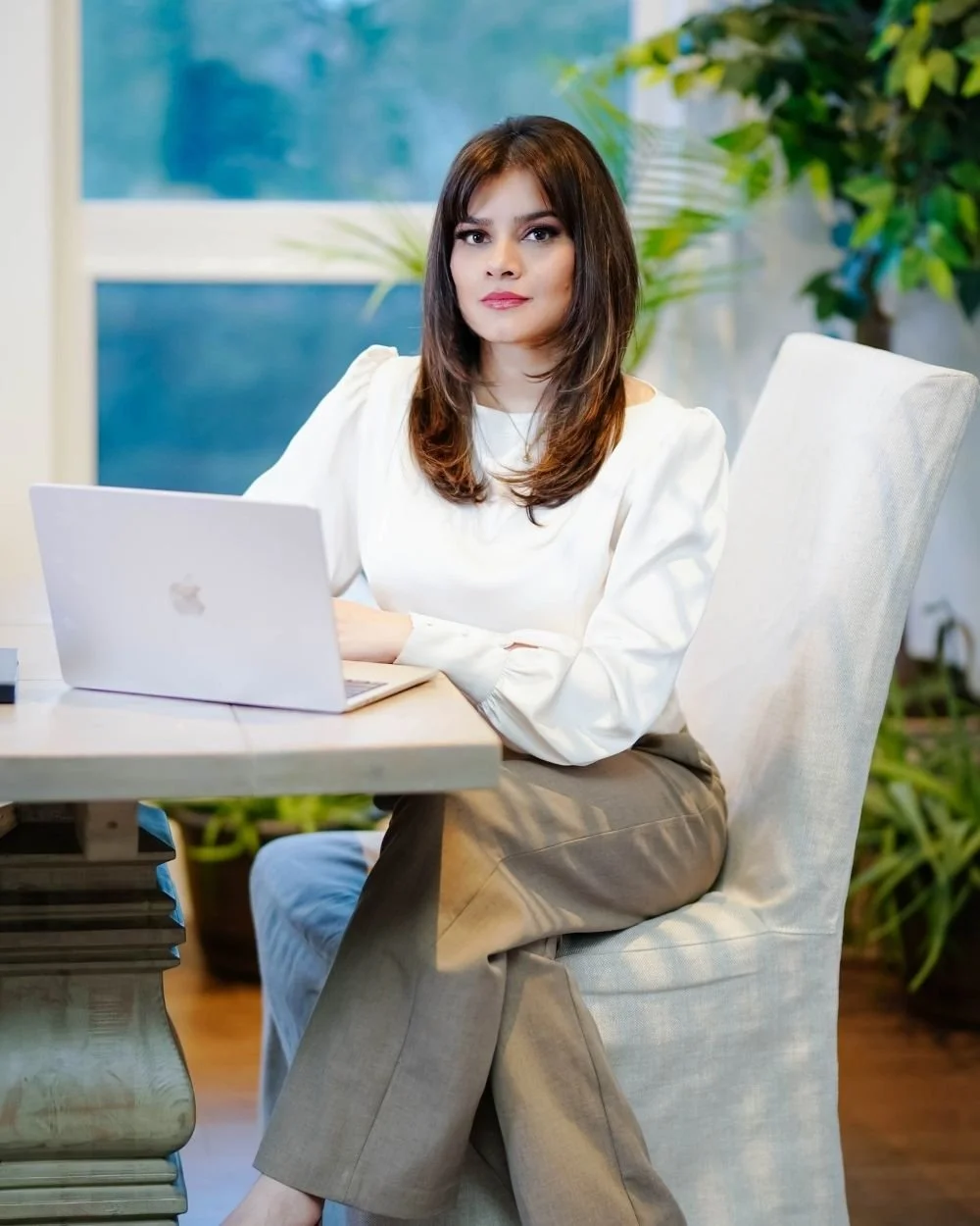 Ayesha sitting at a desk with a laptop at Art of Becoming Counselling