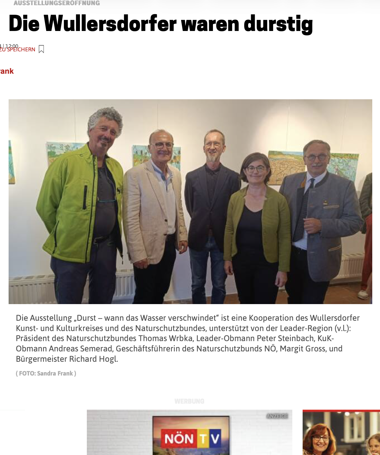 Five people standing together in an art gallery. The group includes three men and two women, all dressed in formal or semi-formal attire. Behind them, there are colorful paintings on the wall.