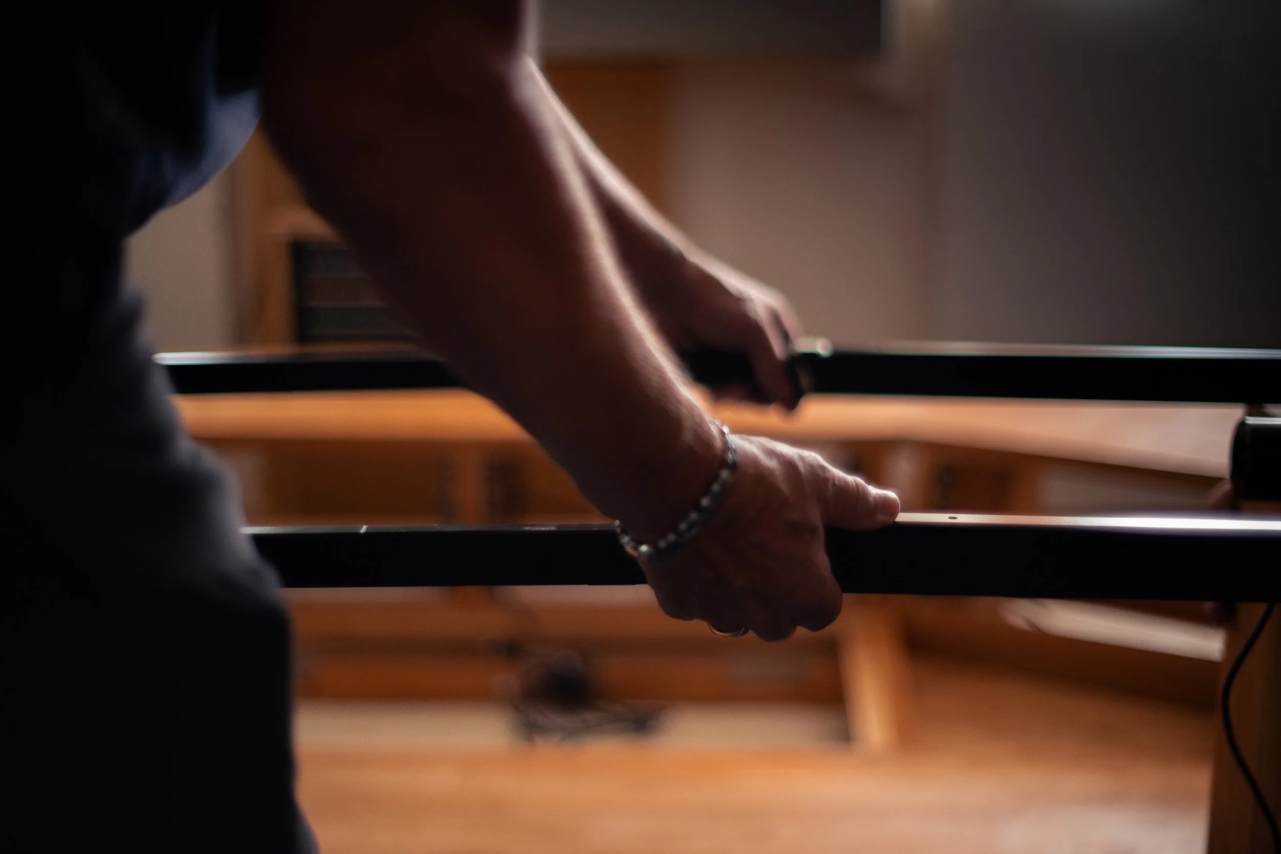 Close-up of a person’s hand pressing keys on a black piano keyboard, with soft lighting.