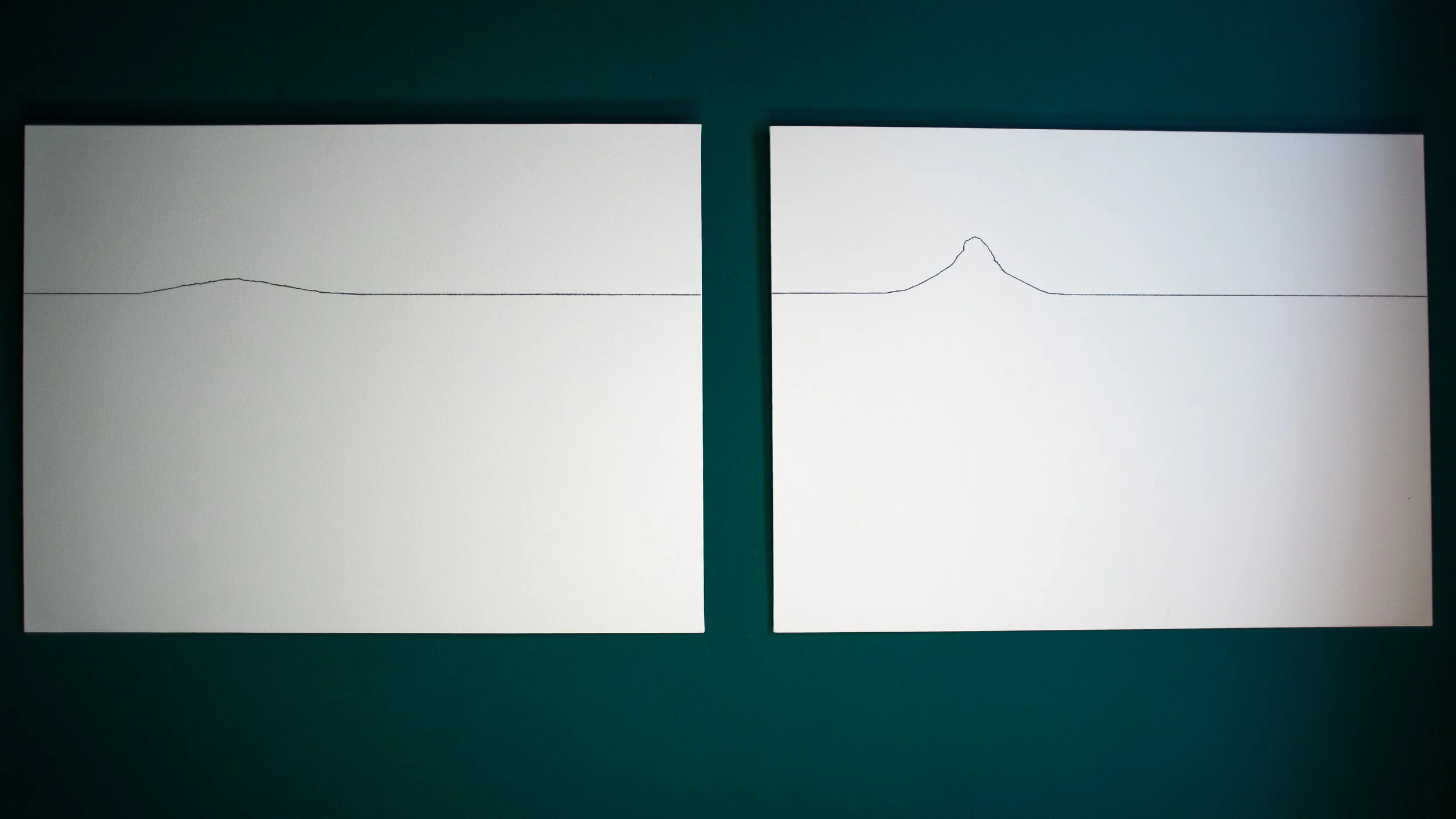 Two Linienbergen artworks displayed side by side, each featuring a hand-drawn minimalist mountain silhouette in black on a white ground.