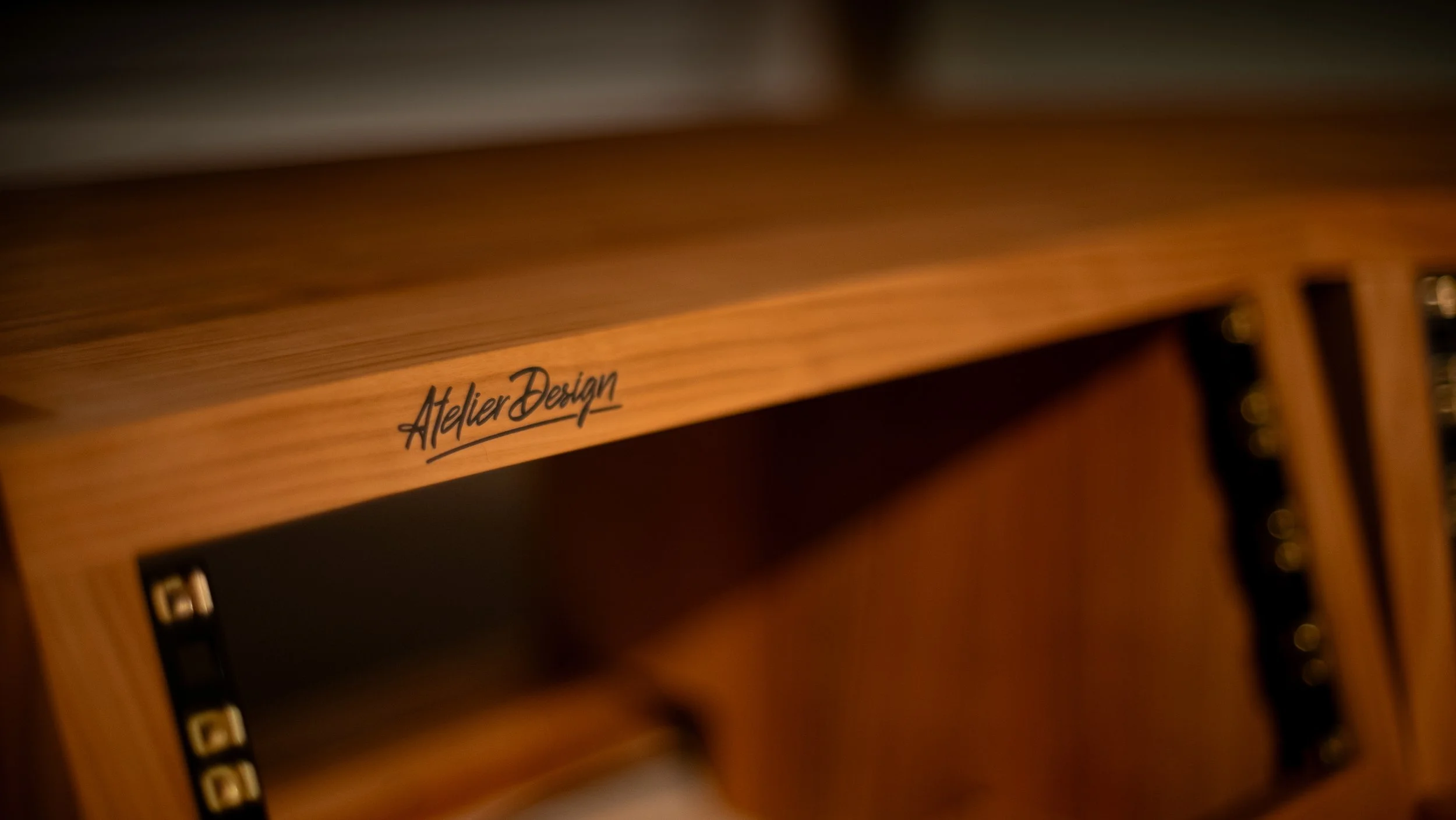 Close-up of a wooden piece of furniture with the words 'Atelier Design' written on it.