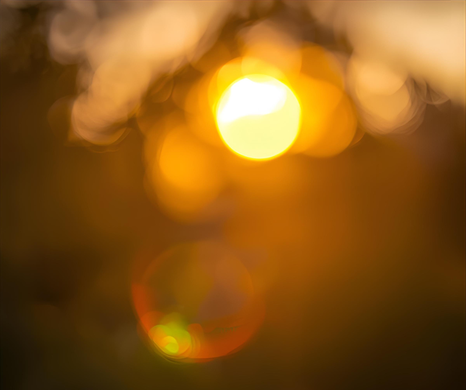 Blurred image of a bright yellow sun with a bokeh effect, creating a warm, glowing atmosphere.