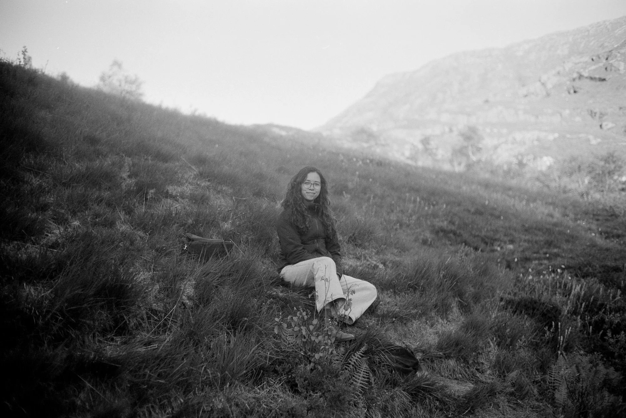 portrait of film wedding photographer Alexa sitting on grass in Glencoe Scotland