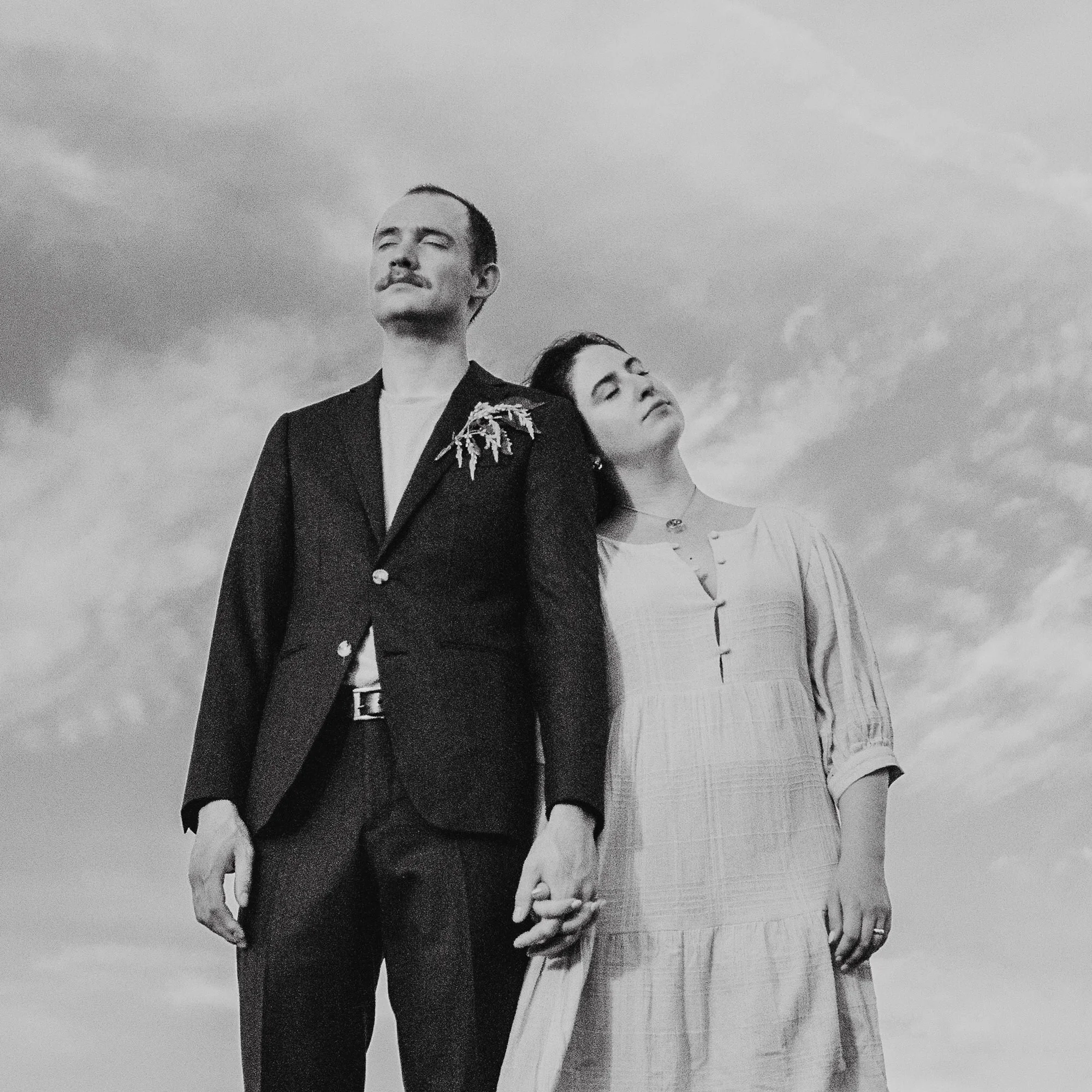 a couple holding hands standing side by side and feeling the sun on their face on a sunny wedding day in asheville nc