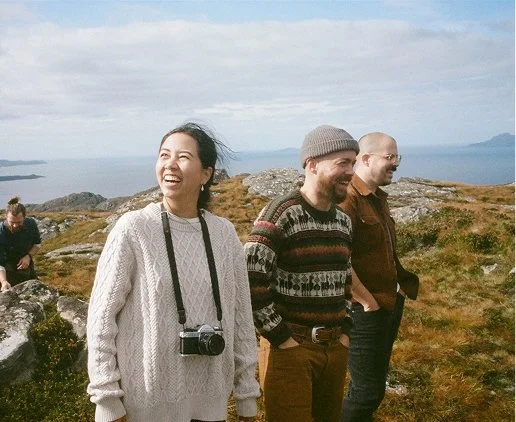 three photographers standing on Scotland mountaintop with ocean in background