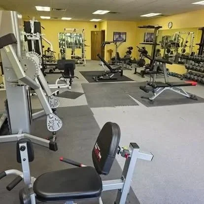 Spacious gym with various workout equipment including weights, exercise machines, and benches.