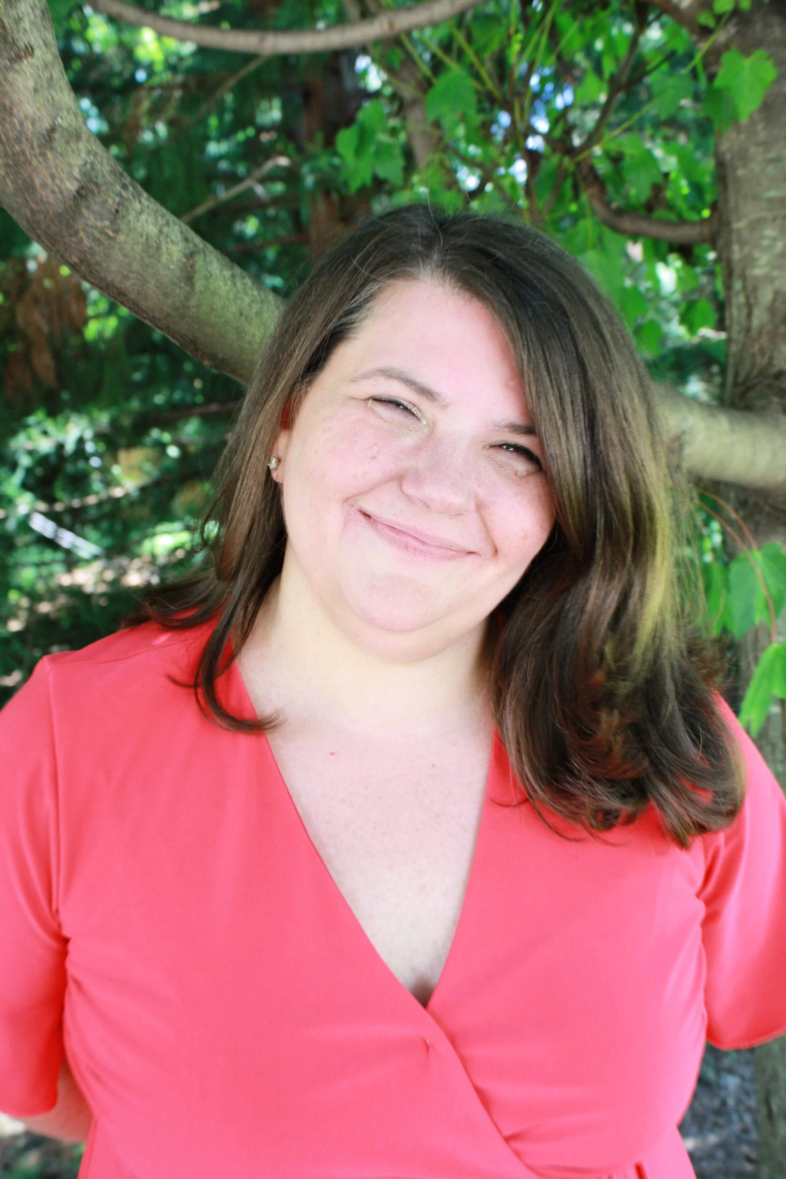 Picture of Jaime Jennings. Hair is long. Head is tilted. Wearing a coral colored shirt. Smiling slightly.