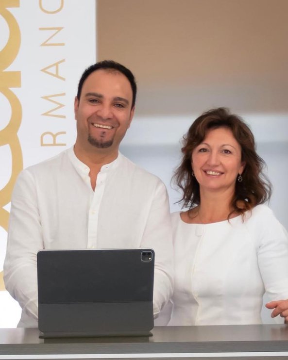 Due persone sorridenti, un uomo e una donna, si trovano davanti a un tablet, in un ambiente professionale.