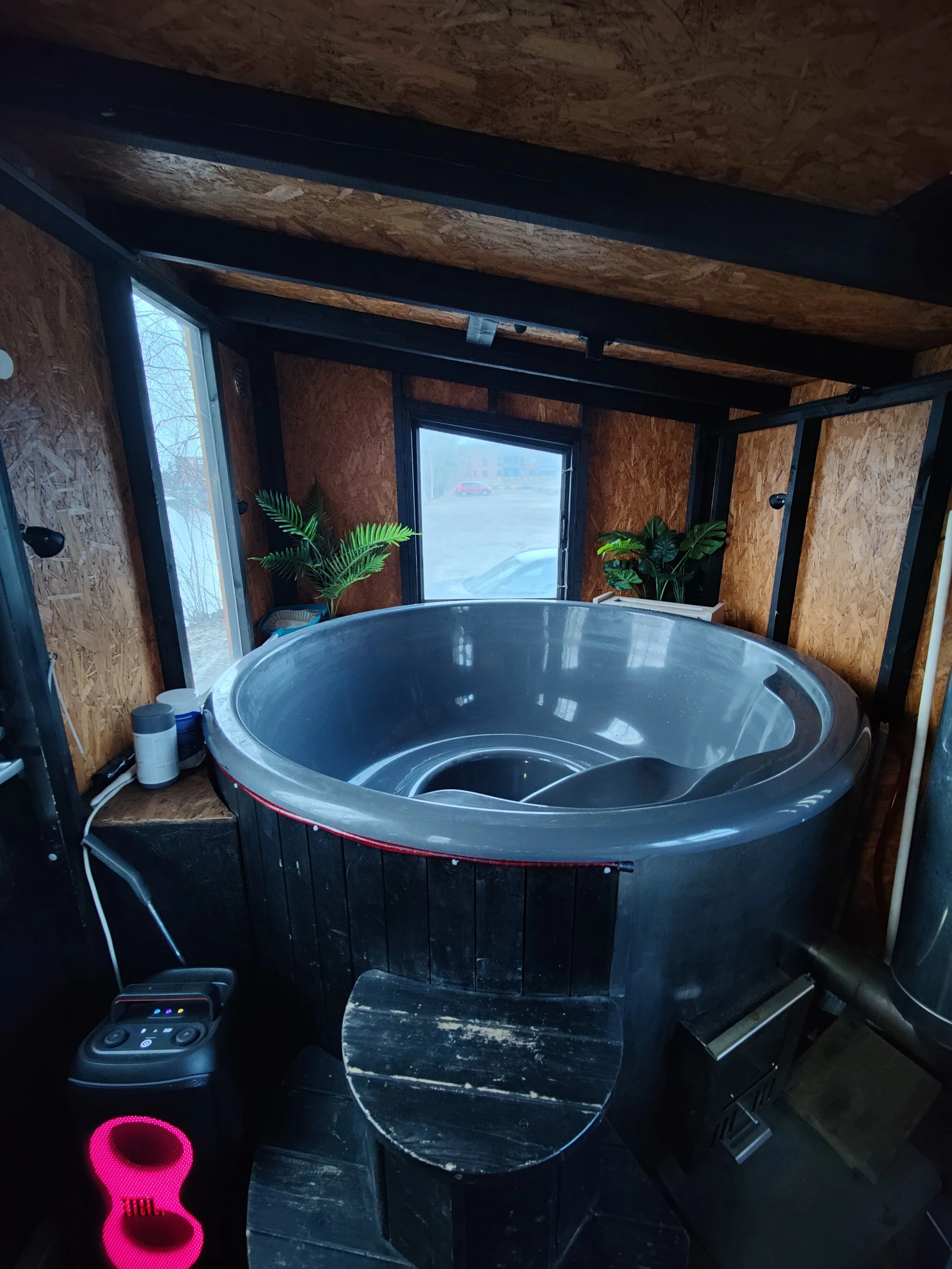 Yksityinen terassiallas, jossa on musta kylpytynnyri ja puita sisältävä ympäristö.