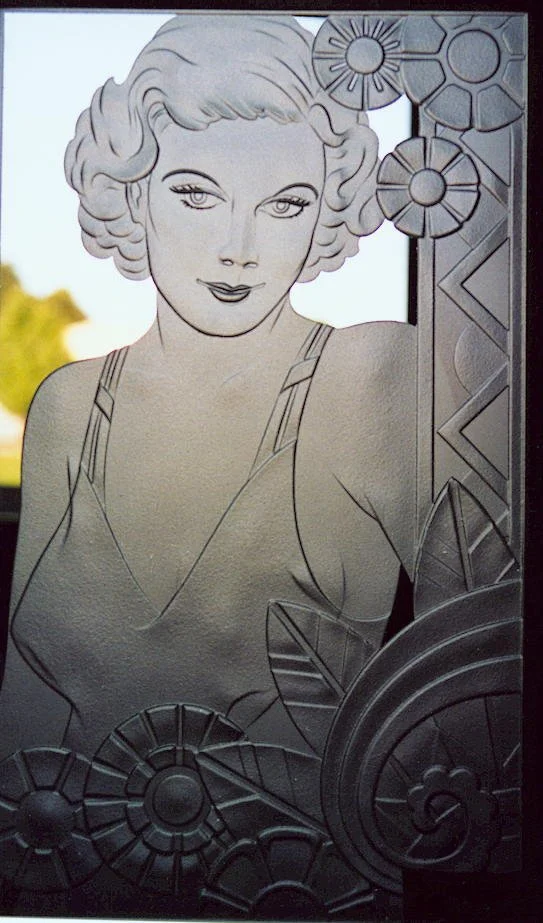 A decorative glass carving of a woman, Jean Harlow, with short curly hair, wearing a sleeveless top, surrounded by art deco geometric and floral patterns.