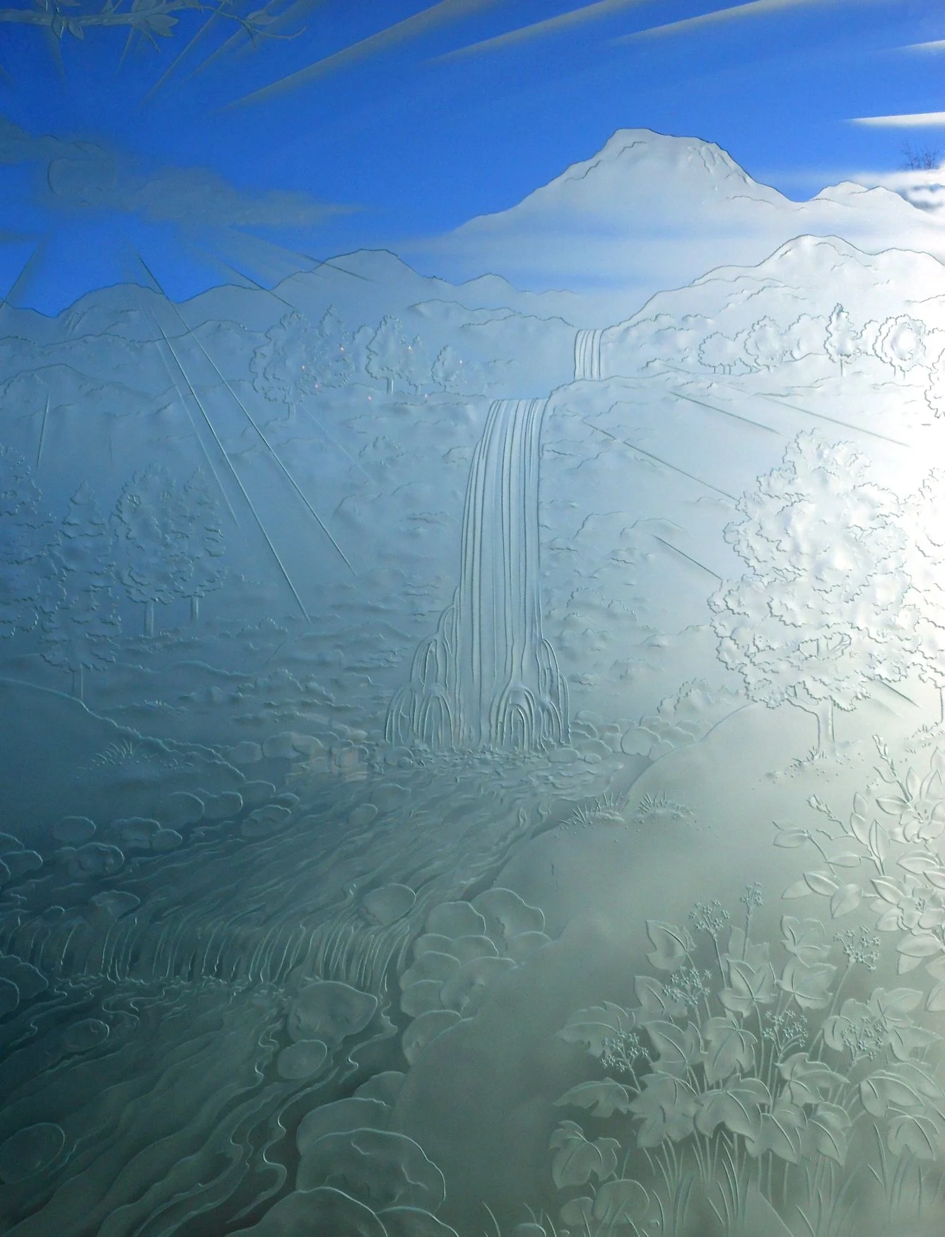 Wall mural of a mountain scene with waterfalls, trees, and a flowing river, painted in shades of blue and white.