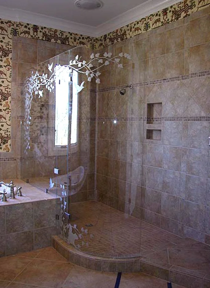 Bathroom with a walk-in shower and a glass door decorated with white floral and bird designs, beige tiled walls, a small window, and a corner bathtub with vintage-style fixtures.