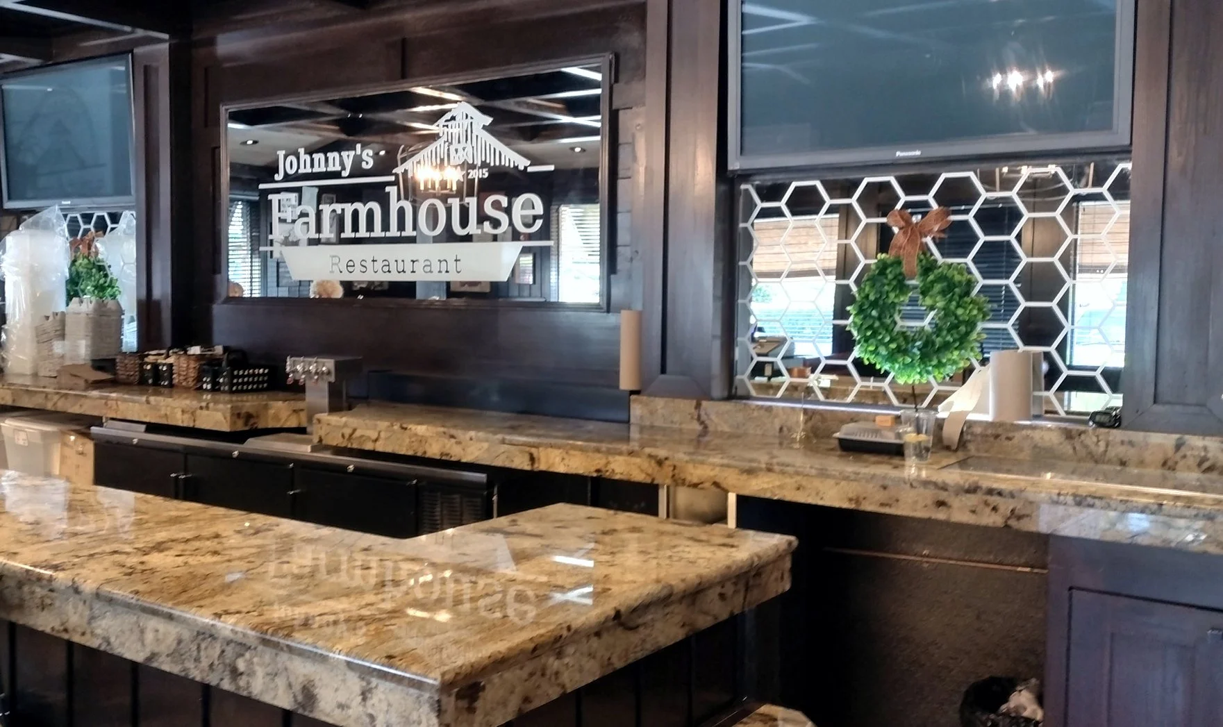 Decorative etch mirror with a honeycomb-patterned and a carved mirror with the logo of Johnny's Farmhouse Restaurant, with granite countertops.