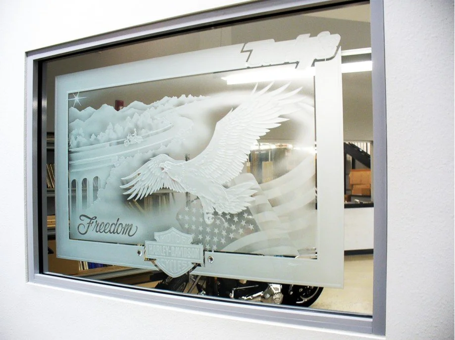 Carved divider glass featuring an eagle with spread wings, an American flag, clouds, and the word 'Freedom' with a Harley-Davidson emblem.