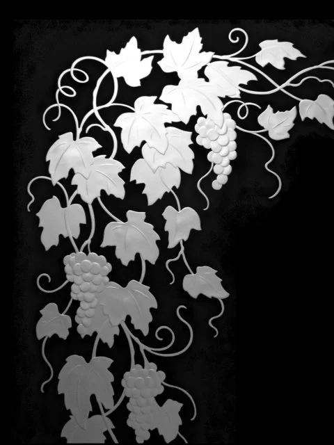 Black and white illustration of grapevine with leaves and grape clusters.