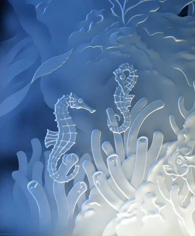 A glowing underwater scene with two seahorses among coral and sea plants.