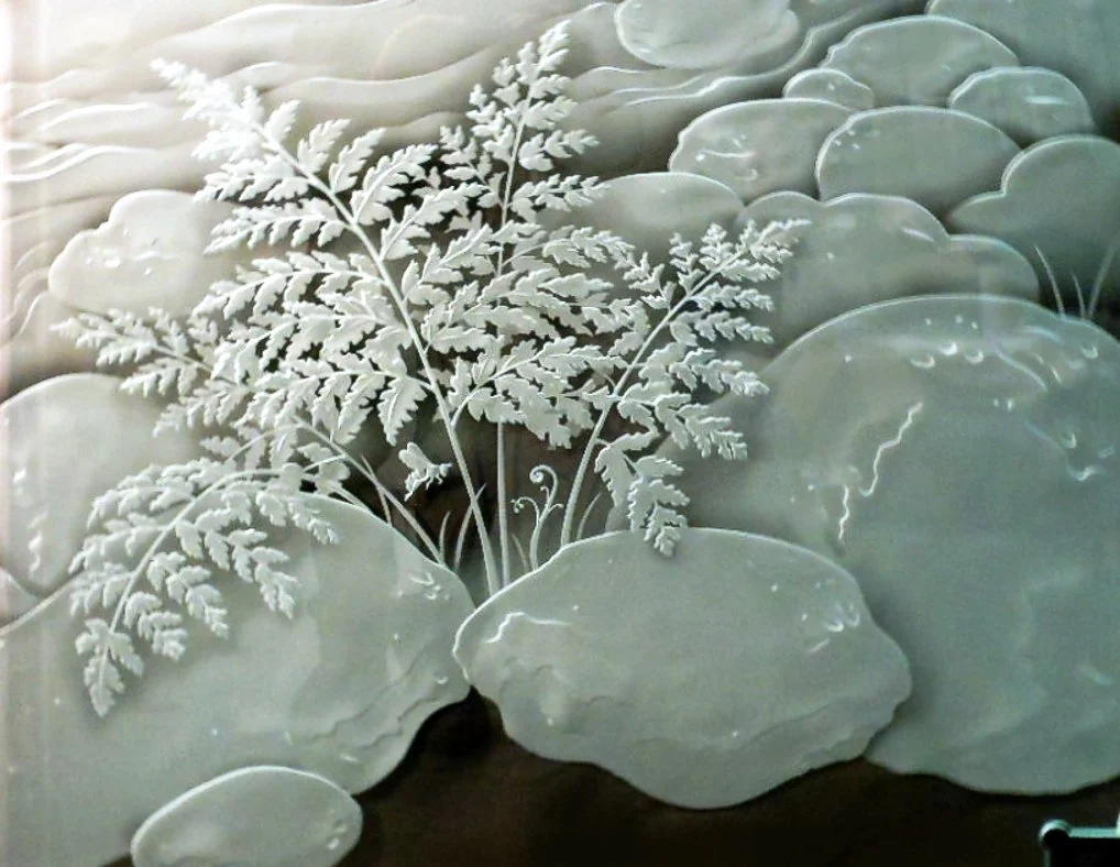 Carved jade scene with fern and clouds.