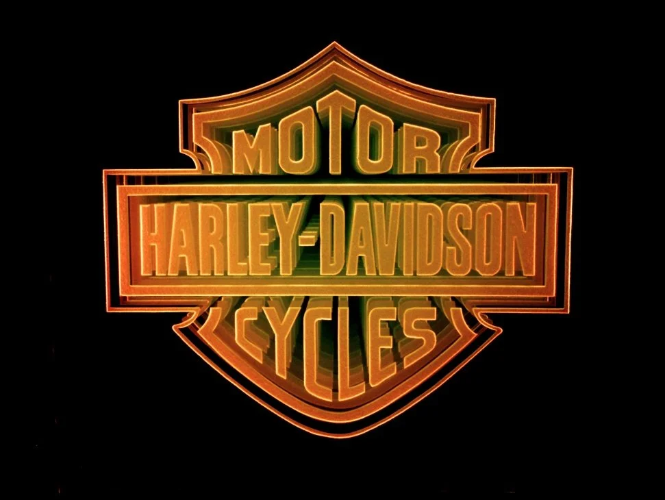 Harley-Davidson Motorcycles logo edge lit glass sign, with orange color on a black background.