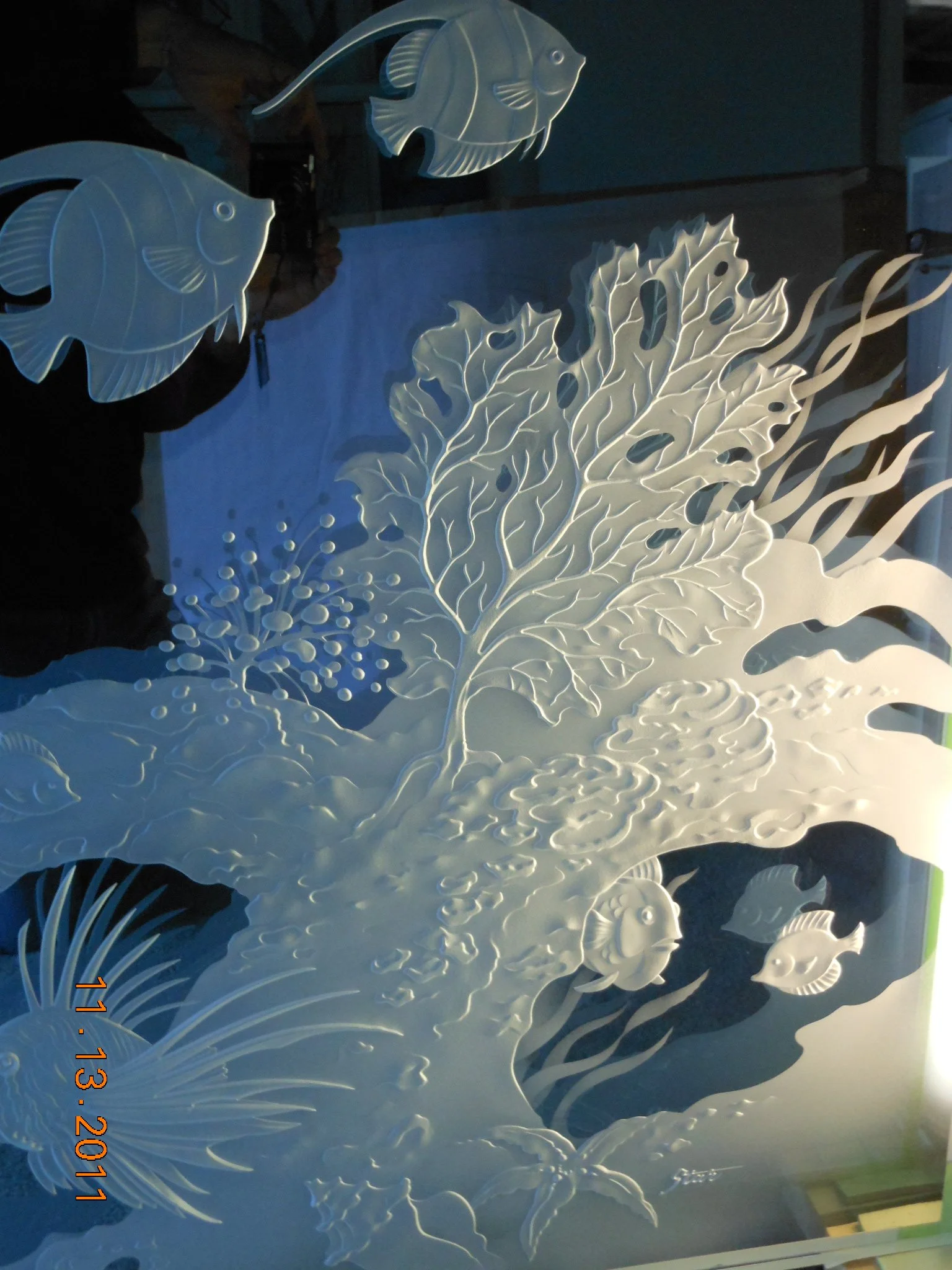 Decorative white paper art depicting an underwater scene with fish, coral, and aquatic plants.