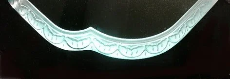 Close-up of an illuminated, decorated glass edge with intricate engravings.