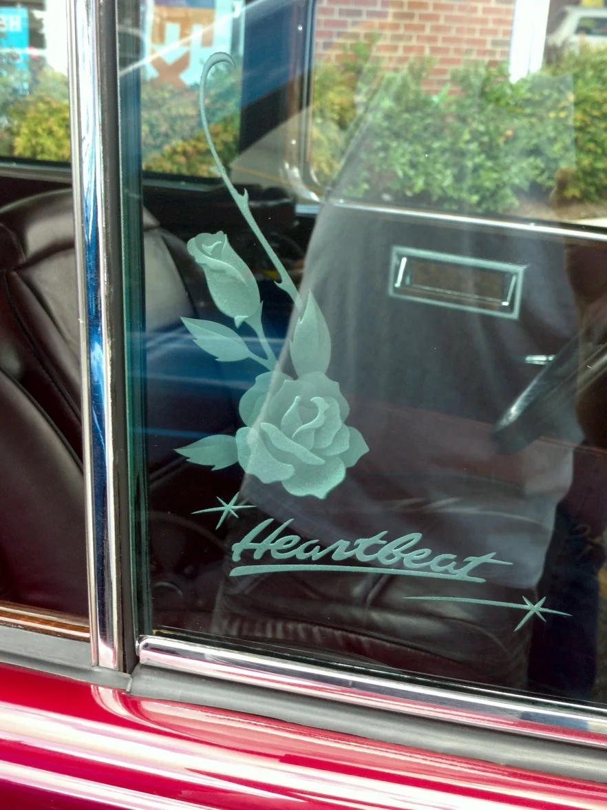 Decorative glass etching on car window featuring a rose and the word 'Heartfelt' with star accents.