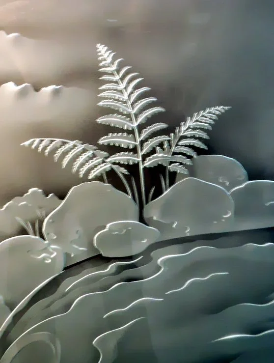 Detail of larger glass art featuring a fern, rocks and water.