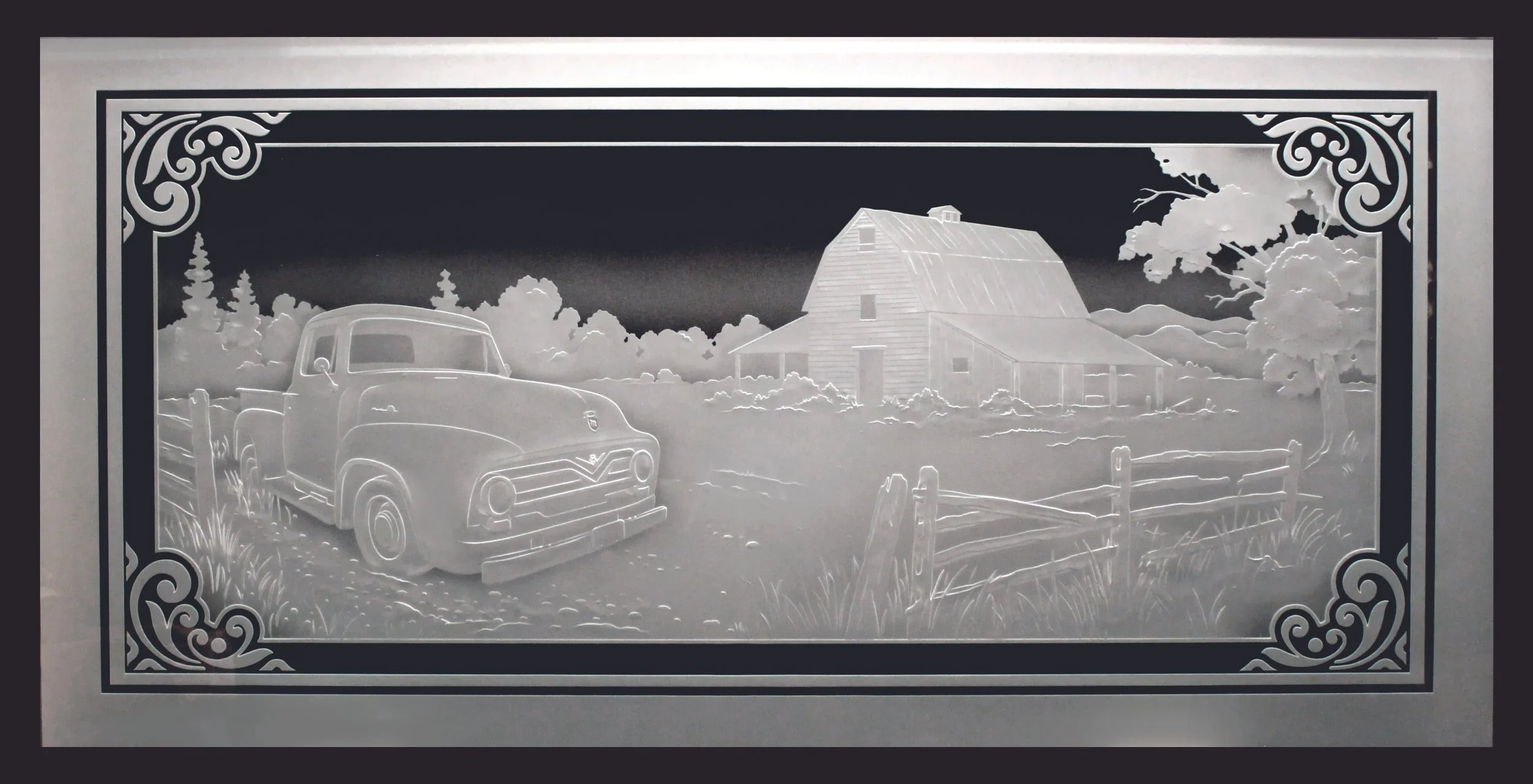 A detailed carved and etched glass art panel of a vintage pickup truck parked on a rural farm with a large barn, trees, fences, and mountains in the background, framed with ornate corners.