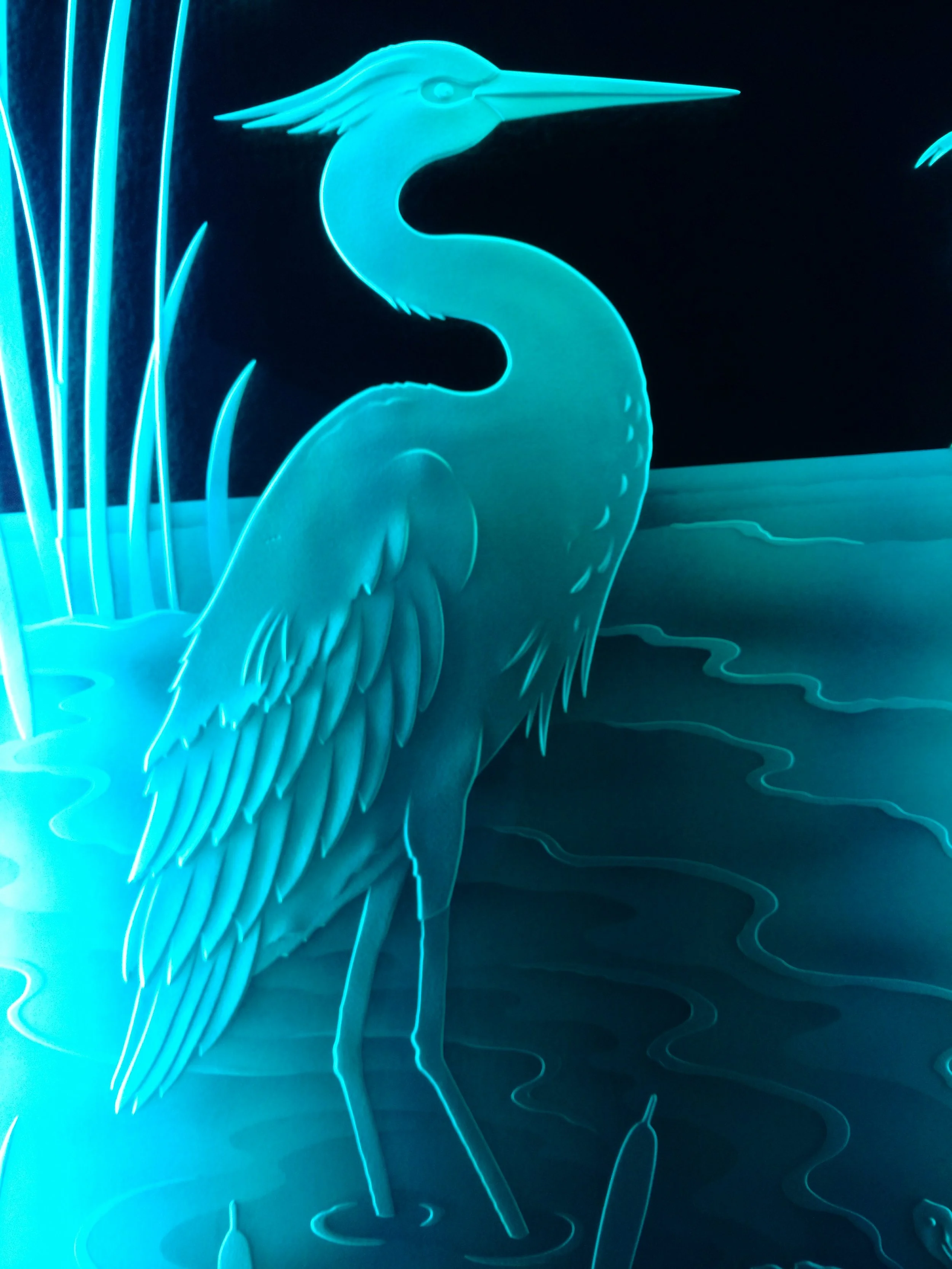 Neon illuminated light art depiction of a heron standing in water with tall grasses in the background.