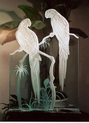 Three decorative glass bird sculptures on a glass base with plant motifs.
