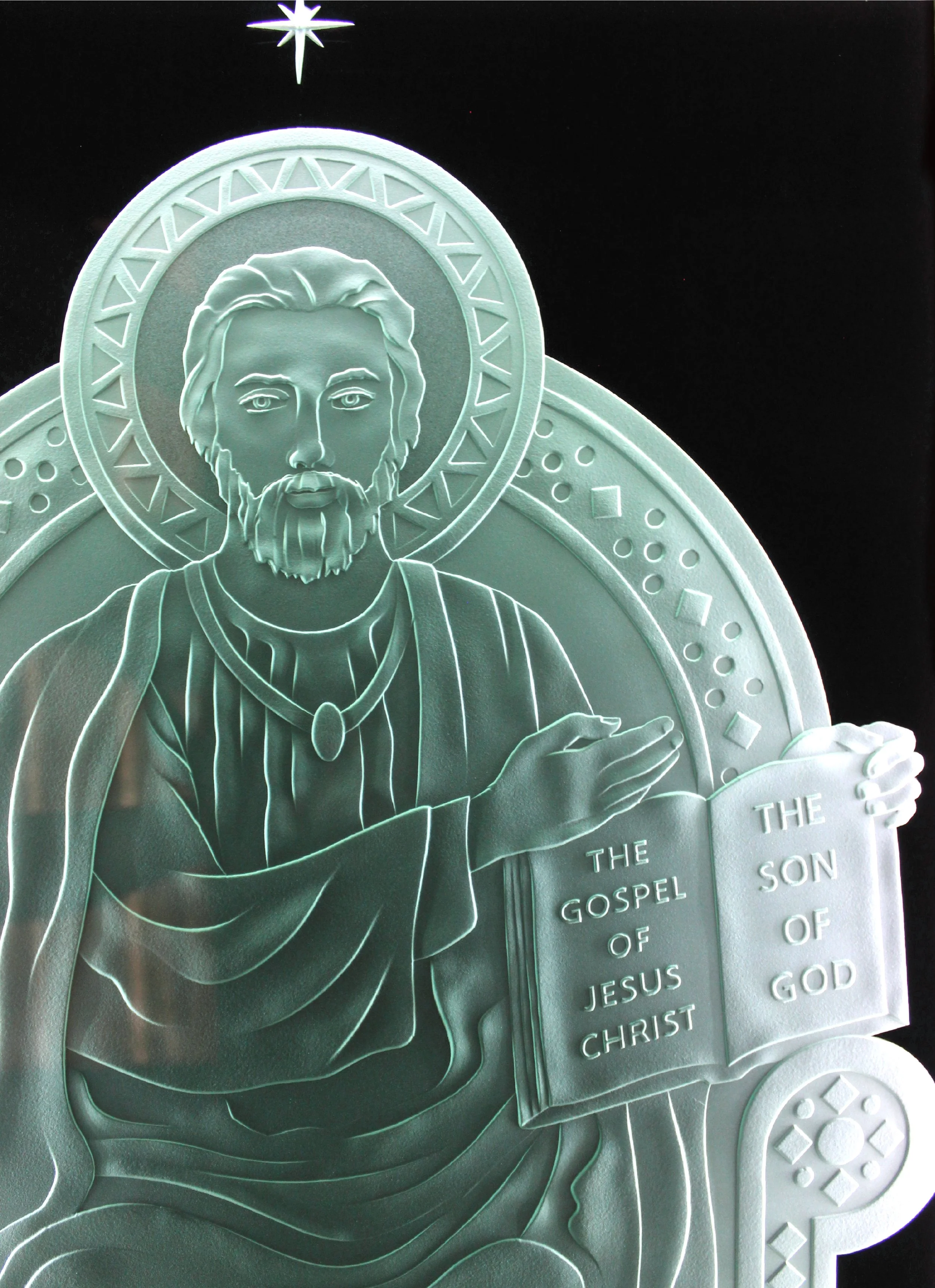 Silver religious plaque depicting Jesus Christ with a beard and long hair, holding an open book that reads "The Gospel of Jesus Christ" and "The Son of God," with a star above and decorative designs around.