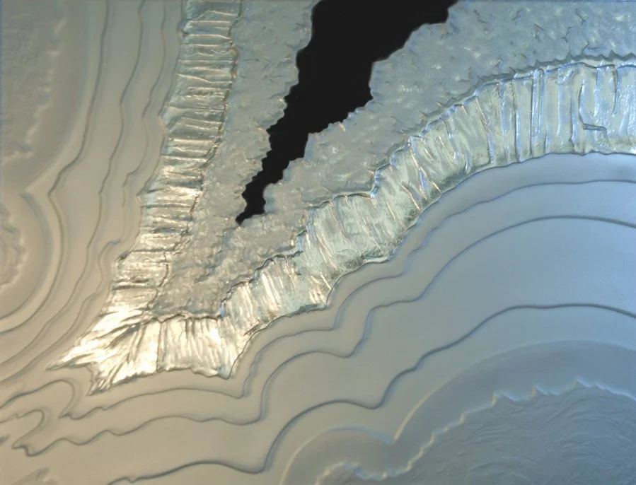 Close-up of a crack and mineral deposits on a metallic surface with layered formations.