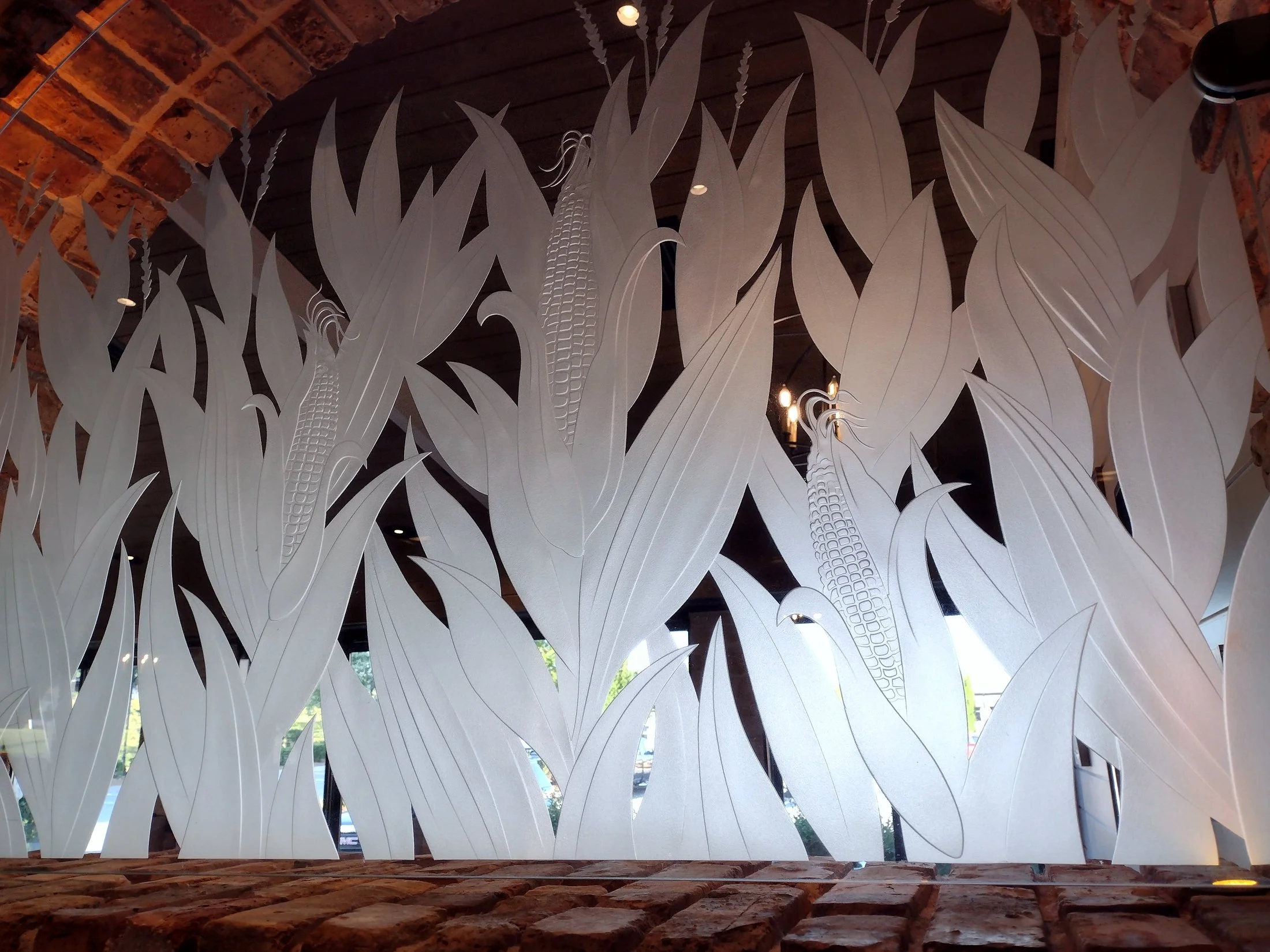 Decorative wall glass featuring large corn stalks with ears of corn, set in brick wall openings.