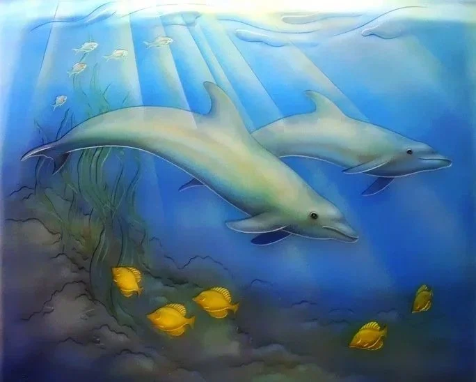 Glass artwork of an underwater scene featuring two dolphins swimming among yellow fish and smaller fish, with sunlight rays penetrating the water surface.