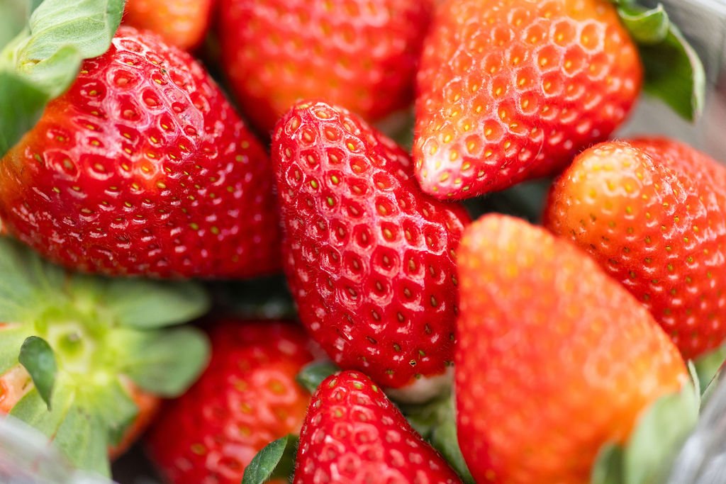 Close-up of fresh, ripe strawberries with green leaves.