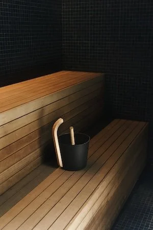 Wooden sauna or steam room bench with a black bucket and ladle. At the wellness club in toronto. Science backed wellness. Wellness event.