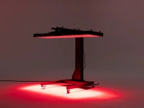 A clinical grade red-light setup with red lighting, set on a table with a red glow on the floor underneath.
