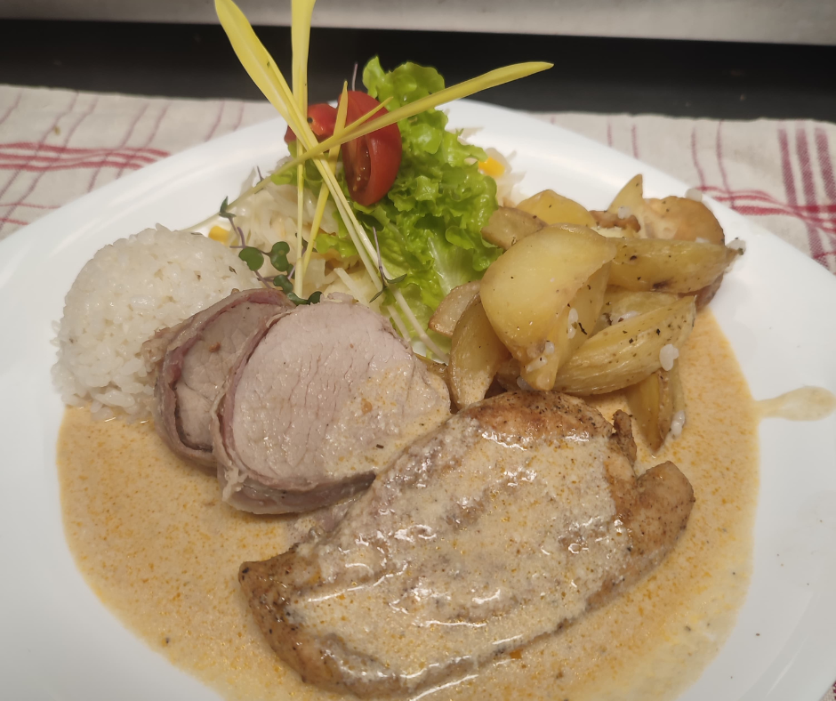 Plate of cooked meat with gravy, roasted potatoes, rice, and salad with cherry tomato and lettuce.