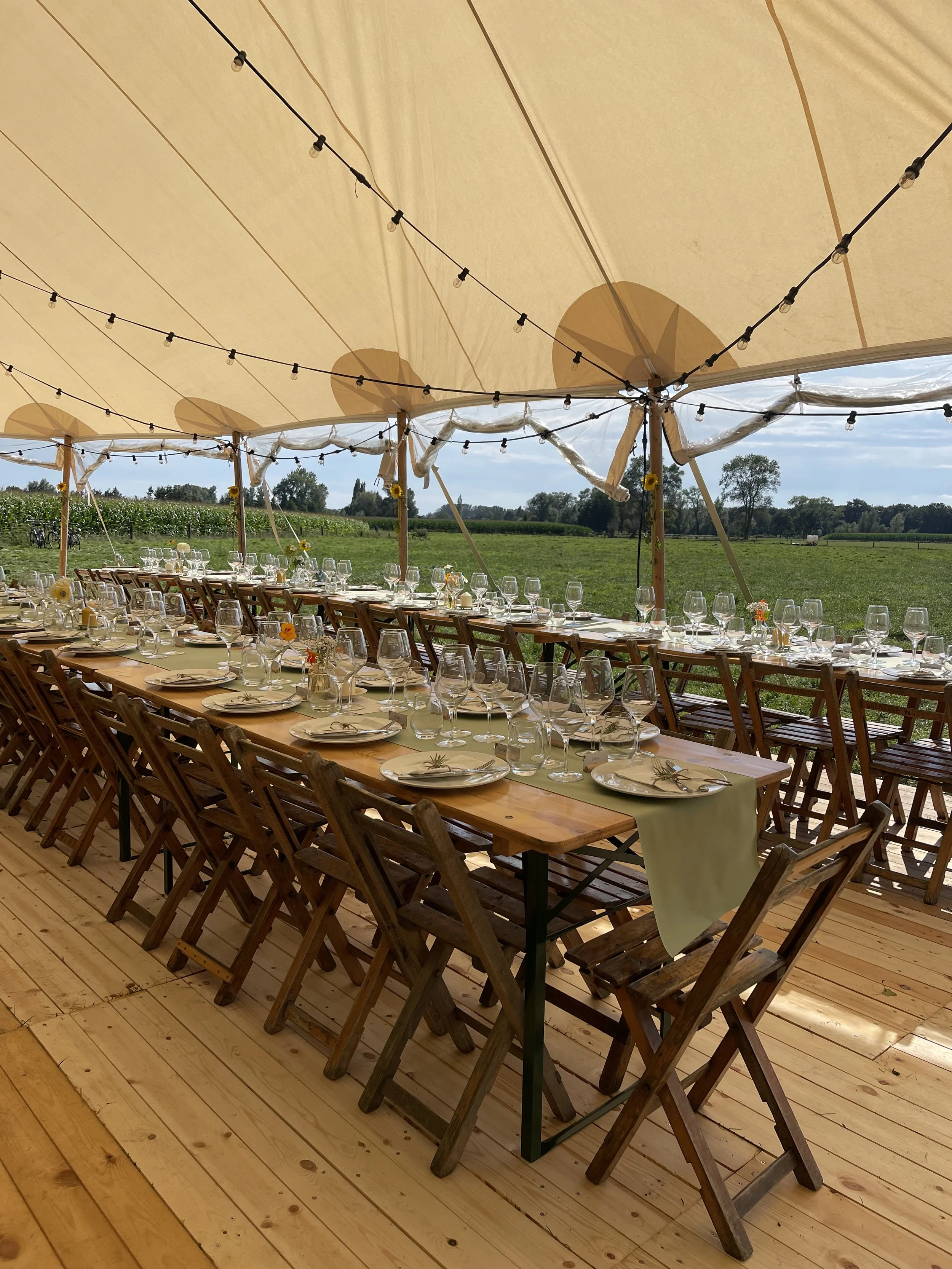 Lang gedekte tafel onder een tent met een uitzicht op een groen veld en bomen.  #chefvandenberghe , chef van den berghe , private dining, private chef aan huis