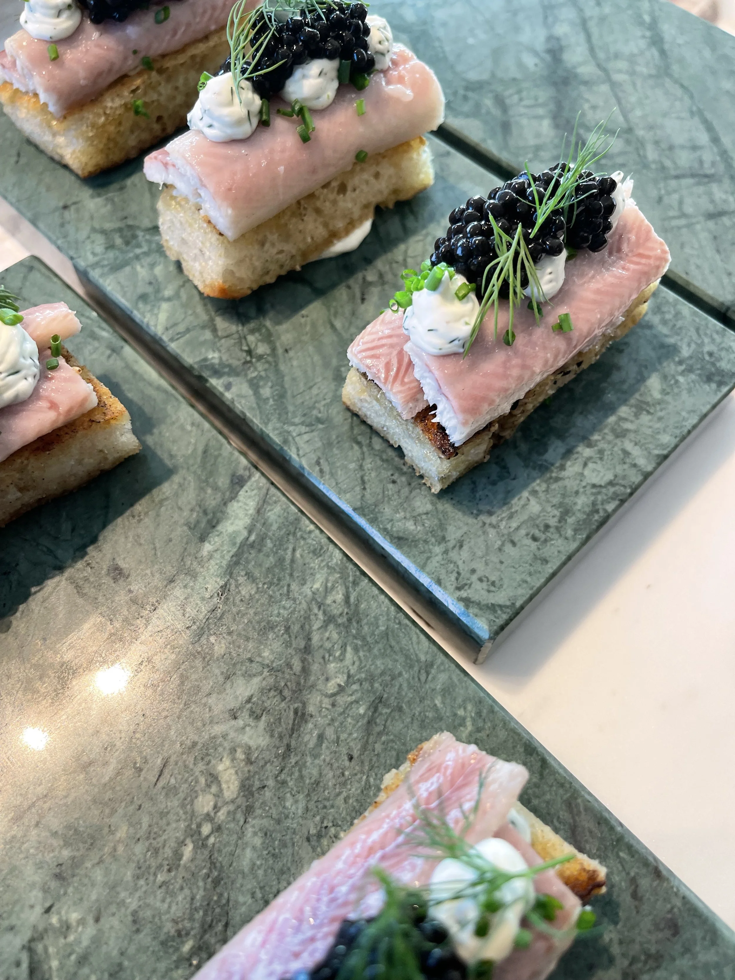 Sandwiches met gerookte zalm, crème, zwarte bessen en groene kruiden op groene stenen platte #chefvandenberghe , chef van den berghe , private dining, private chef aan huis