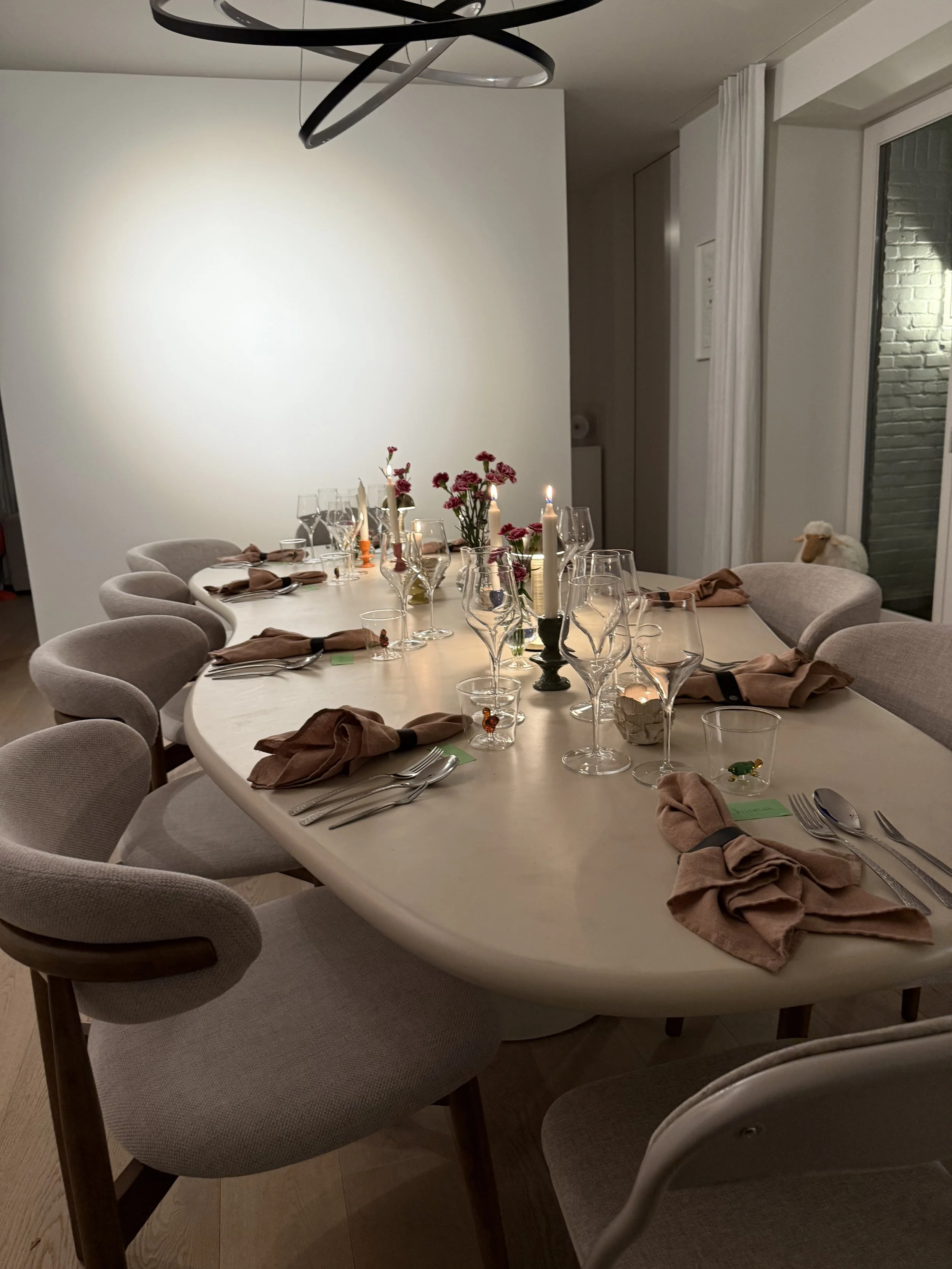 Een feesttafel met gedekte tafellinnen, glazen, bestek, kaarsen en bloemen, klaar voor een diner. #chefvandenberghe , chef van den berghe , private dining, private chef aan huis