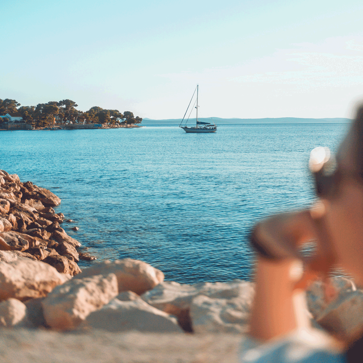 a person sitting out by a body of water. relaxing on holiday as a yacht sails past. relaxed in the peace of mind that their pensions are supported